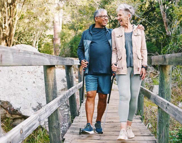 Relax, senior or couple of friends hiking, walking or trekking for freedom, exercise or fitness in nature forest. Interracial, travel or happy woman enjoys bonding time with healthy elderly partner