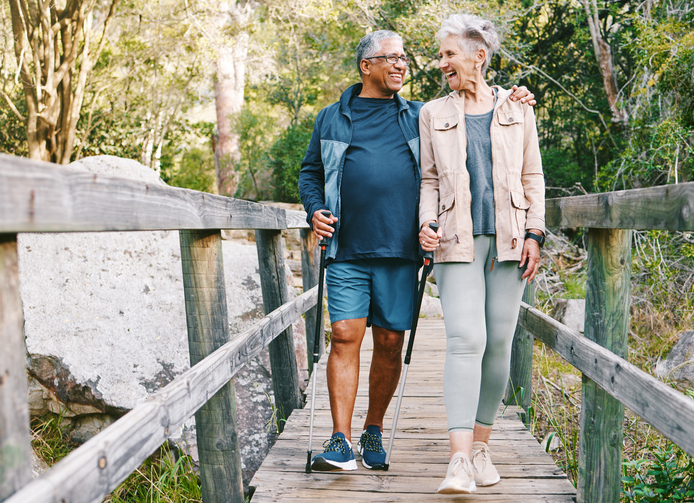 Relax, senior or couple of friends hiking, walking or trekking for freedom, exercise or fitness in nature forest. Interracial, travel or happy woman enjoys bonding time with healthy elderly partner