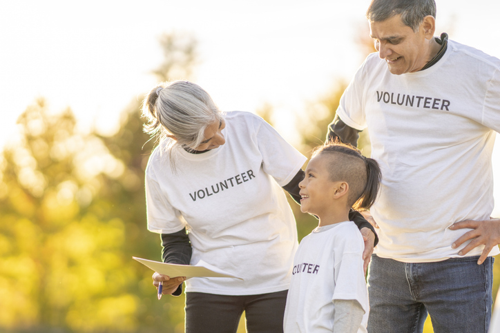 A young boy and his grandparents assemble outside together on a sunny day as they volunteer their time in the community.